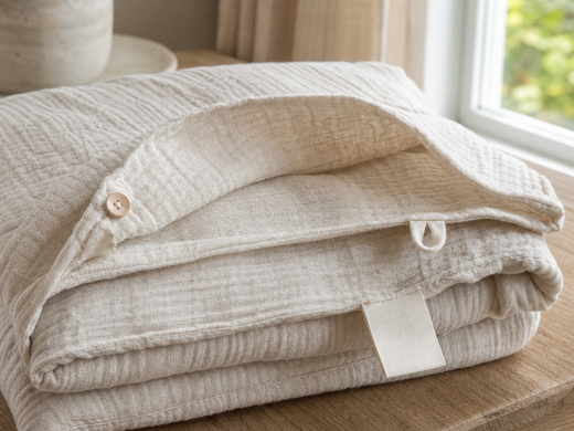 Folded crinkled gauze bedding with a button-and-loop closure and blank fabric tag