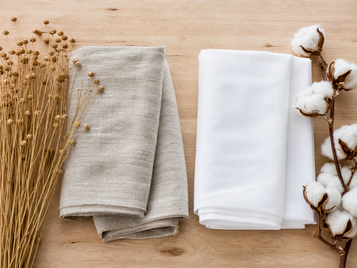 Flax stems and textured linen fabric beside cotton bolls and smooth cotton fabric