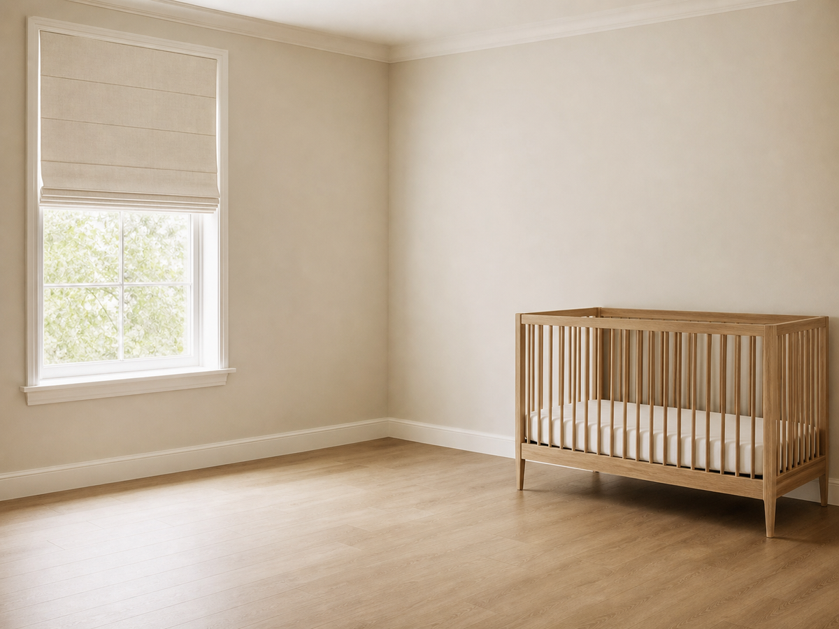 Nursery window shade with no visible cords and an empty crib positioned across the room from the window