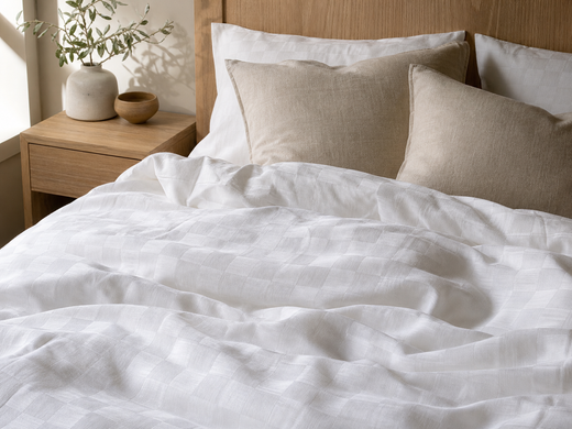 White checkered duvet cover layered with oatmeal pillows and a light wood nightstand